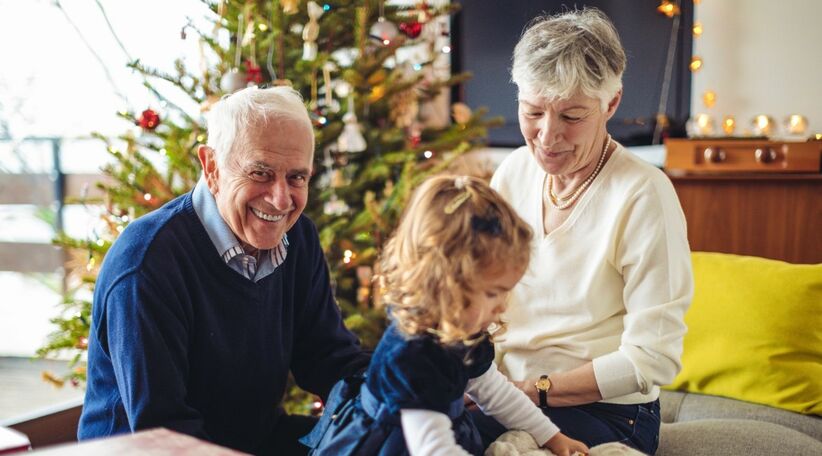 Préfon Retraite : des grands parents souriants avec leur petite-fille près du sapin